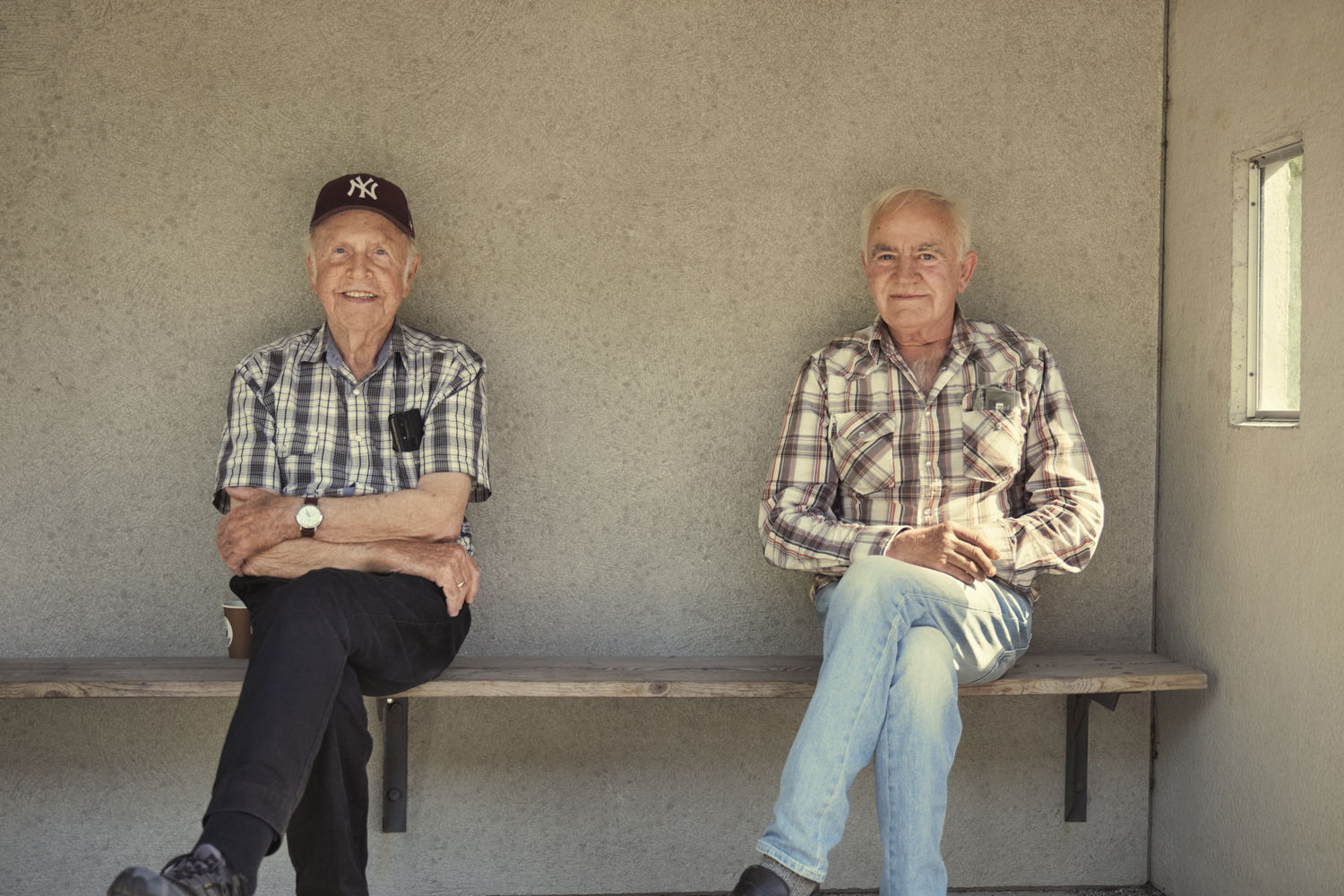Pensjonistar sitjande på ein benk i eit busstopp.