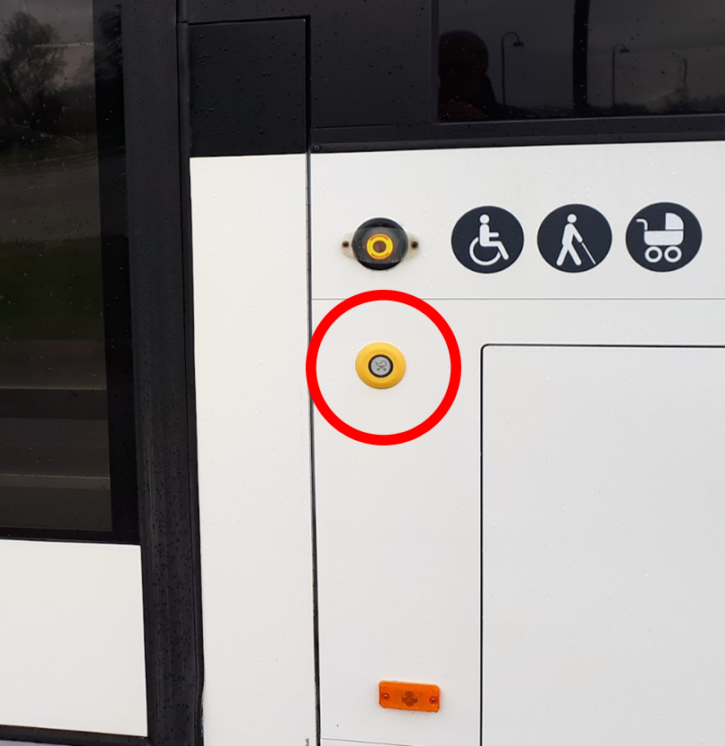 Bildet viser knapp med barnevogn-symbol på utsiden av bussen ved siden av bakre inngang. Knappen kan benyttes for å signalisere for sjåføren at man trenger lengere tid. 