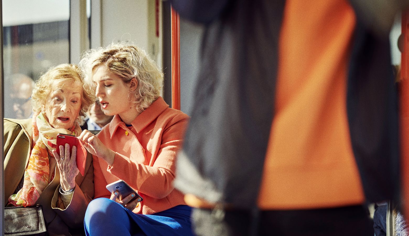 To kvinner, ei eldre og ei yngre, sit saman på bybanen og ser på ein telefon. Foto: Morten Wanvik.