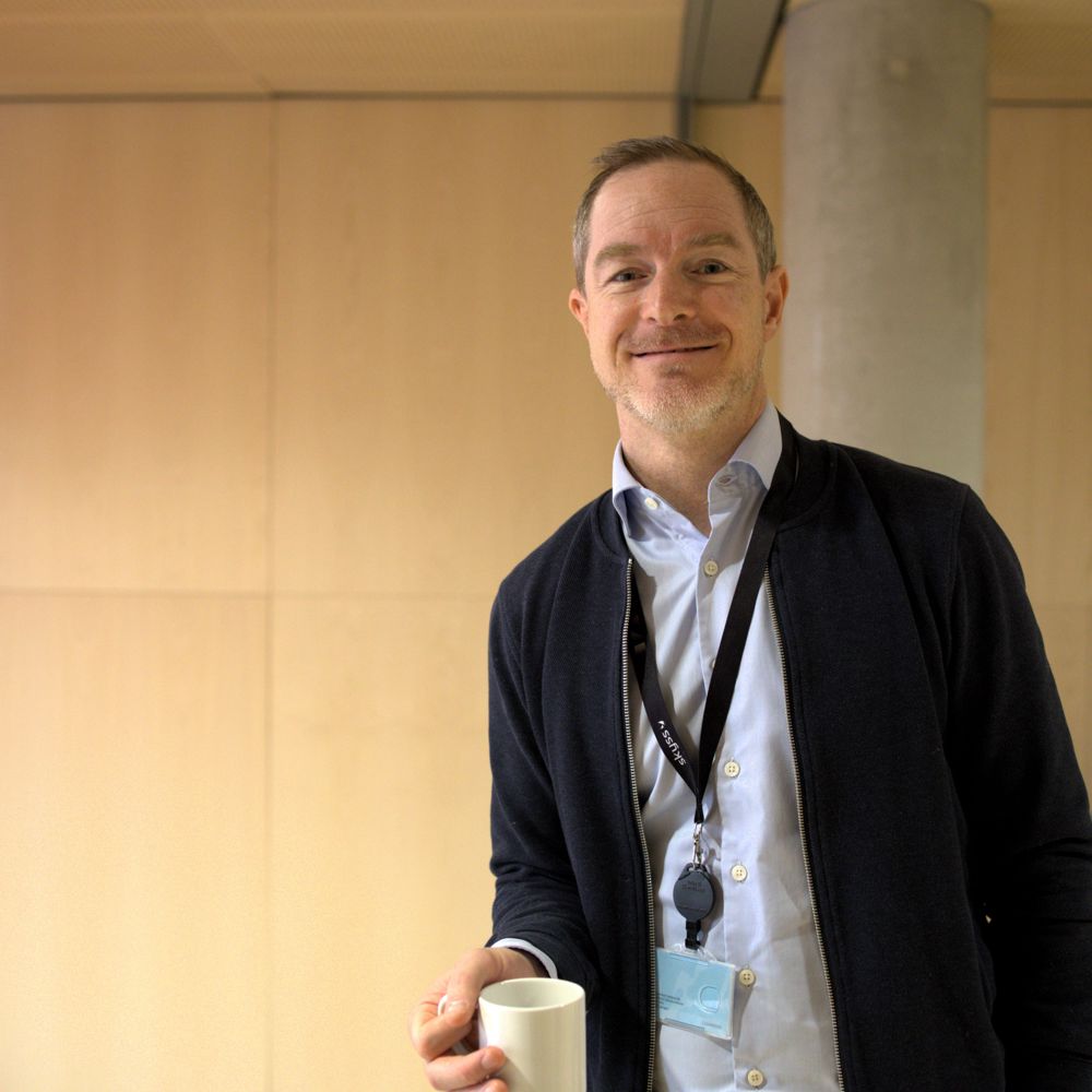 Bilete syner Daniel Michel Nilssen på Vestlandshuset med ein kaffikopp i handa medan han smiler
