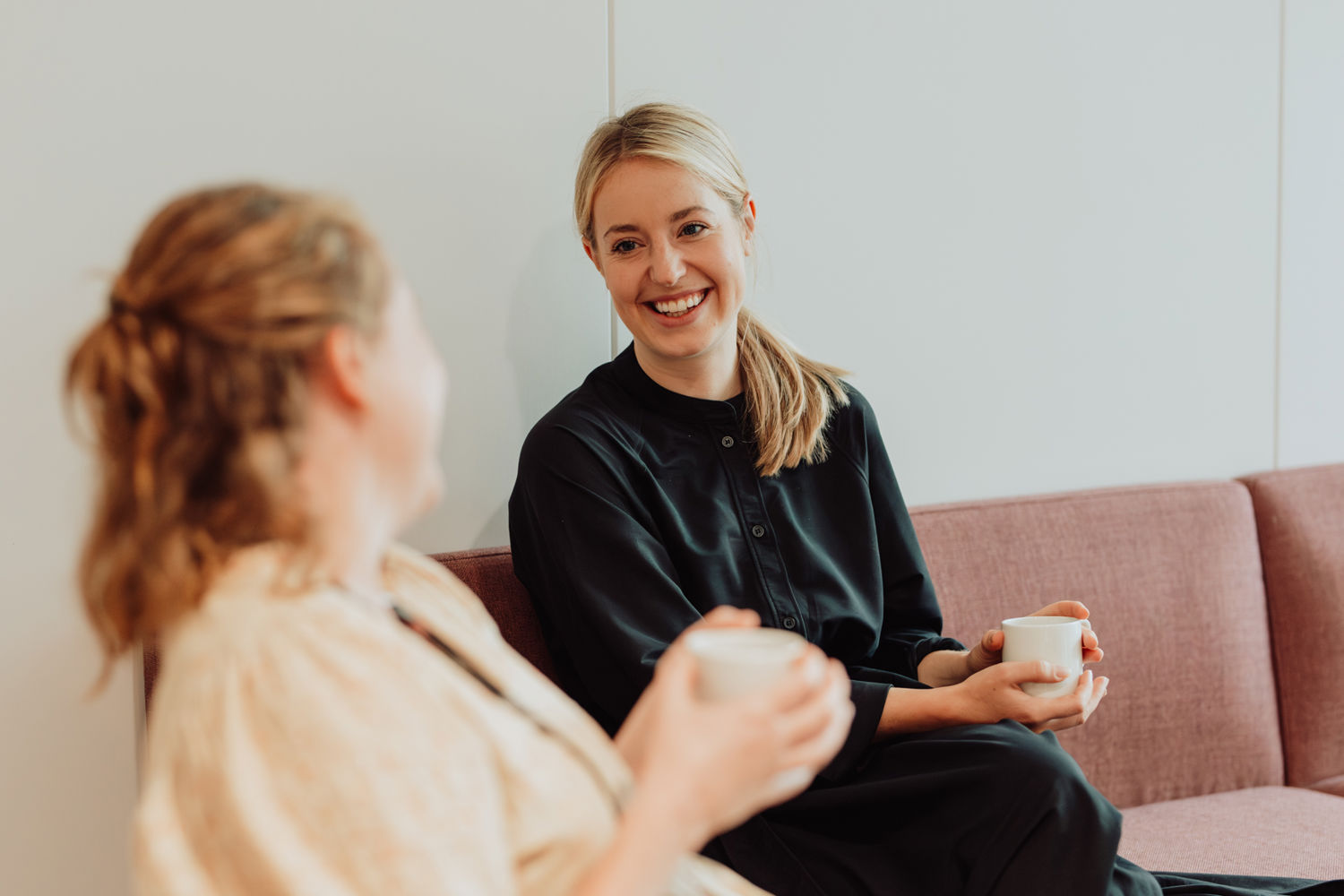 Bilde av Hanne i en sofa med en kaffekopp i hånden. Hun snakker med en annen kollega.
Foto: Skyss/Karoline Rage